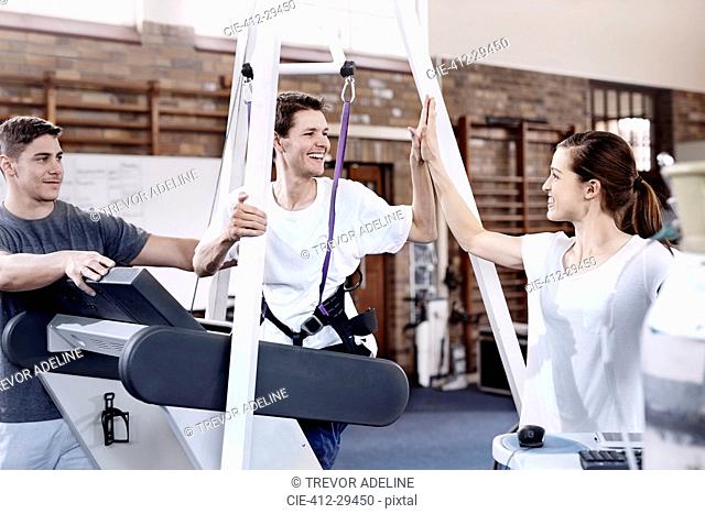 Smiling man high fiving physical therapist