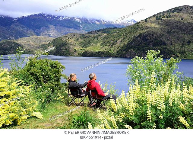 Couple on camping chairs at Lago Tranquilo, Valle Exploradores, near Puerto Rio Tranquilo, Región de Aysén, Chile