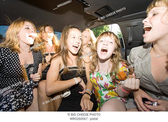 Group of teenaged girls singing in limousine