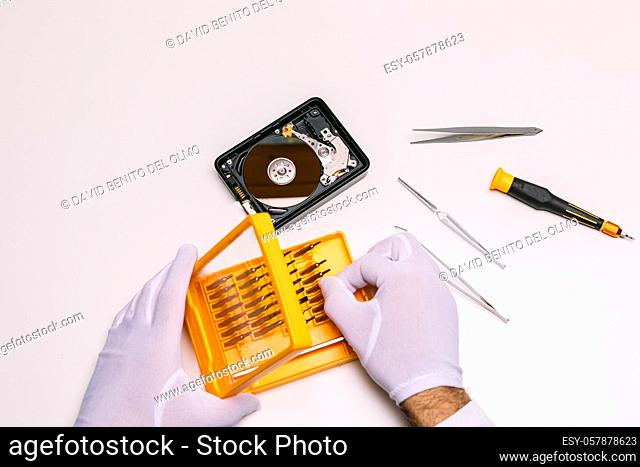 Hands of a technician with gloves repairing a hard drive. Technology maintenance concept