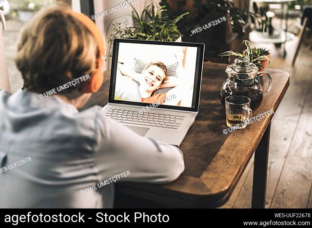 Mother having video call with smiling daughter through video call on table at home