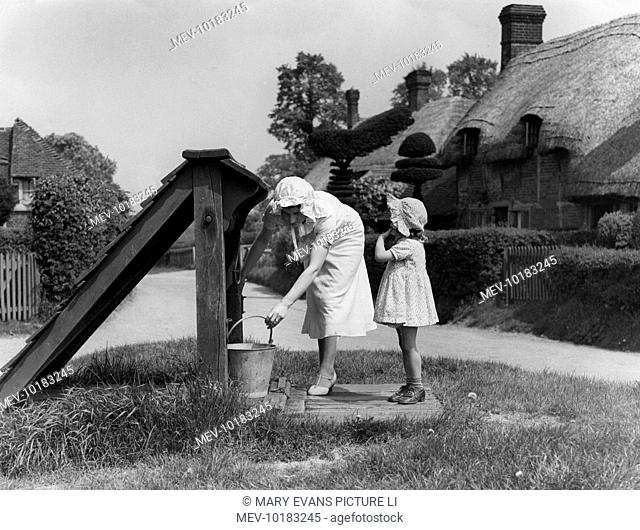 A mother and child fetch a pail of water from the well in the village of Old Basing, Hampshire. England