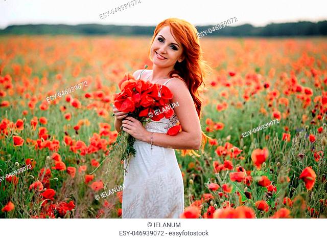 beautiful young woman in poppy field holding a bouquet of poppies, summer