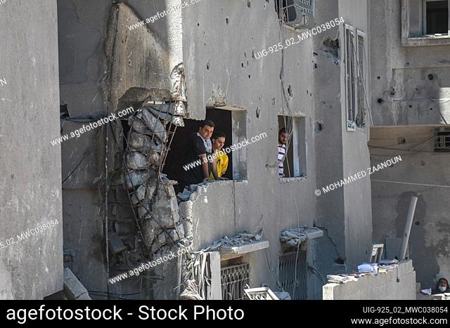 People looking out of damaged buildings due to air strikes. Gaza City