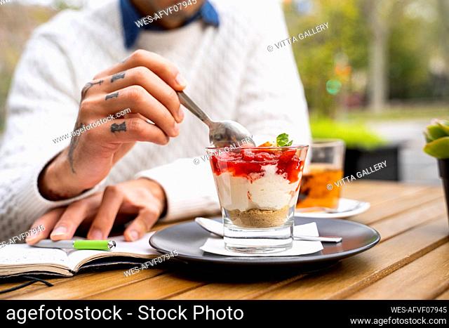 Man scooping dessert with spoon at cafe