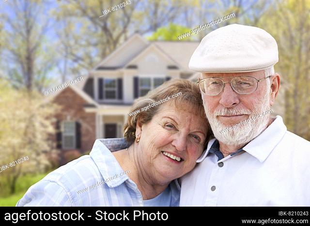 Attractive happy senior couple in front yard of house