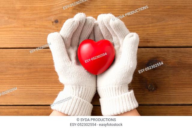 hands in white woollen gloves holding red heart