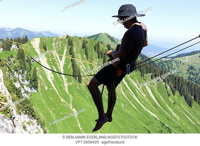 man sitting on highline in Bavarian alps, near mountain Blankenstein, south of Germany