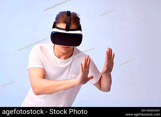Young man in white shirt using virtual reality headset trying to touch objects in virtual reality