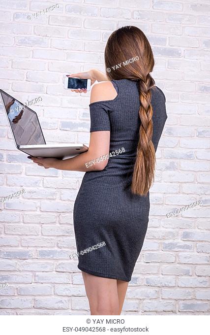 Young beautiful girl model with long hair imitates business lady, office manager or administrator with notebook and telephone