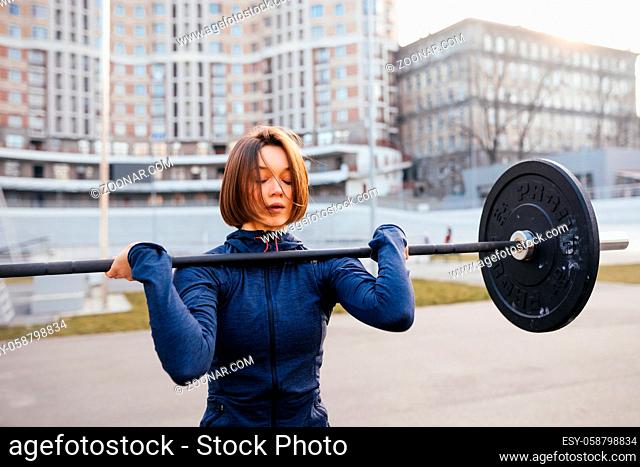 Strong woman exercising with barbell. Cute girl preparing for weightlifting workout. Sports, fitness concept