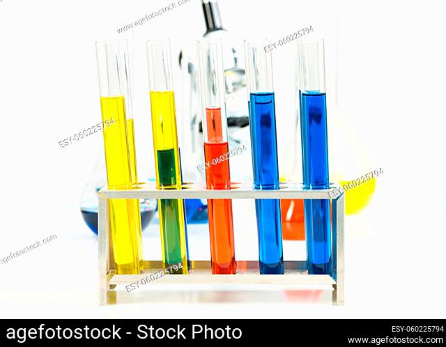 Chemistry lesson in school lab. Glass test tubes with color reagents and microscope standing on desk. Modern school education and experiments in laboratory