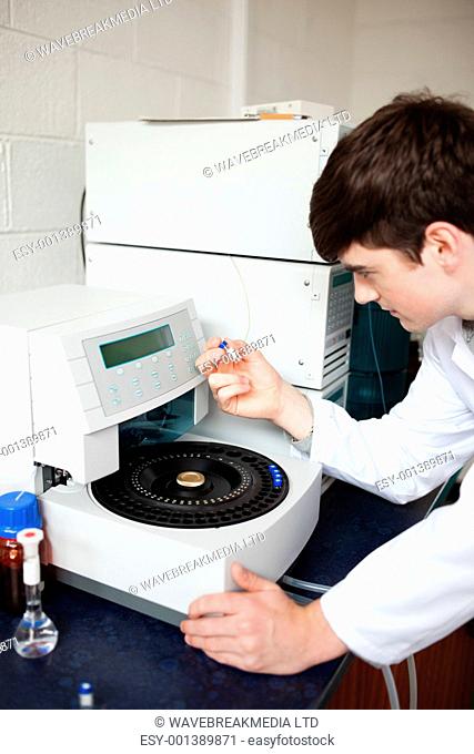 Male laboratory assistant using a centrifuge while looking at a tube
