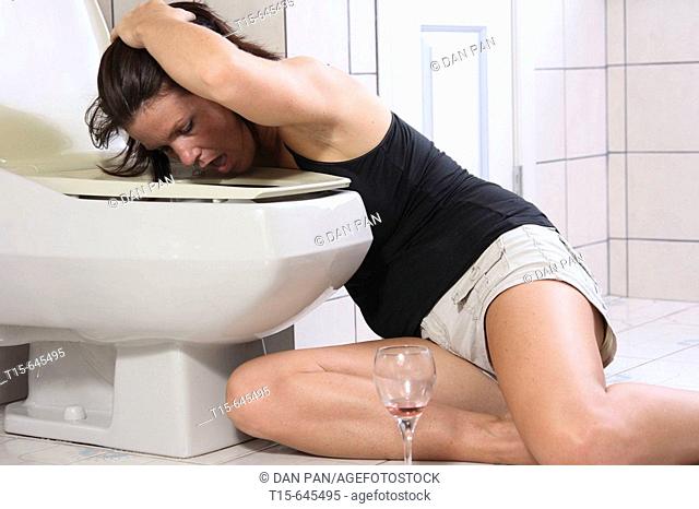 Woman in her 30's having a hang over throwing up on a toilet