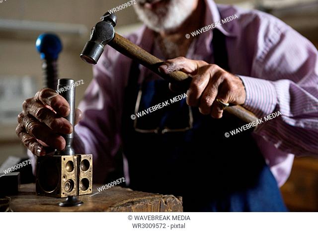 Goldsmith using hammer in workshop