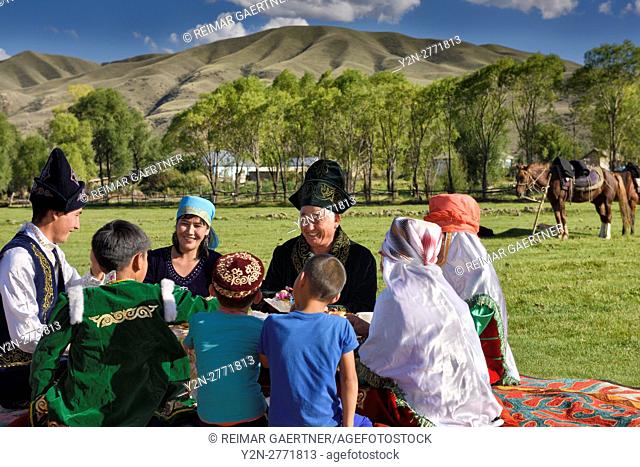 Laughing family in traditional garb at a picnic in pasture of Chilik river valley at Saty Kazakhstan