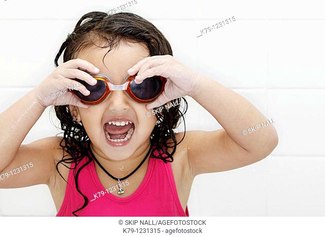 Little girl in swim suit and swim goggles with excited look on her face