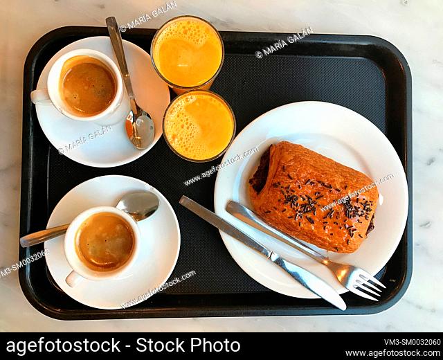 Two cups of coffee, two glasses of orange juice and cake on a tray. View from above