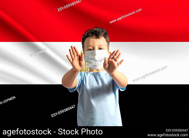 Little white boy in a protective mask on the background of the flag of Egypt Makes a stop sign with his hands, stay at home Egypt