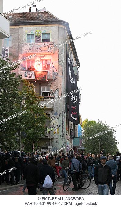 01 May 2019, Berlin: Supporters of the left-wing radical ""Revolutionaries 1 May Demonstration"" stand with pyrotechnics and flags in their hands on a balcony...