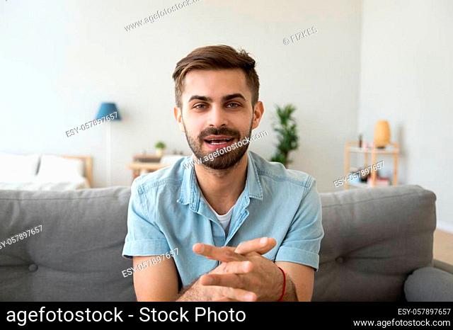 Young guy speaking recording vlog at home looking at camera webcam, male vlogger talking shooting video blog webinar making online call