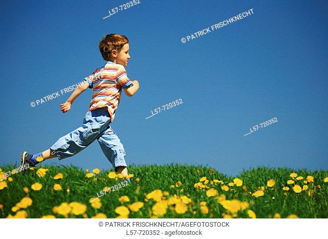 Boy running through filed of Dandelions, in spring, Switzerland