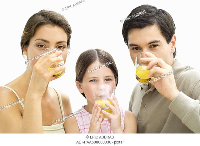 Family drinking orange juice, all looking at camera