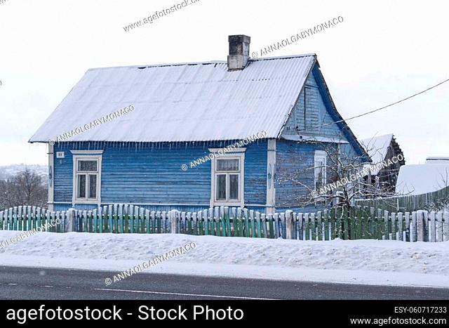 Typical old blue wooden house in snow of winter day