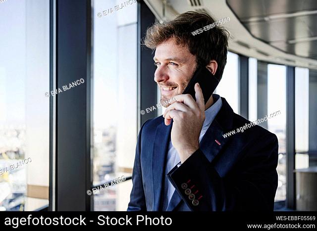 Happy businessman talking on smart phone in office