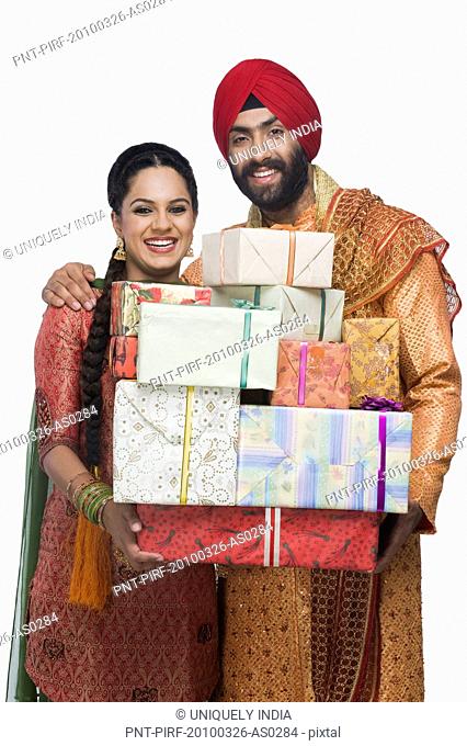 Sikh couple holding stack of presents