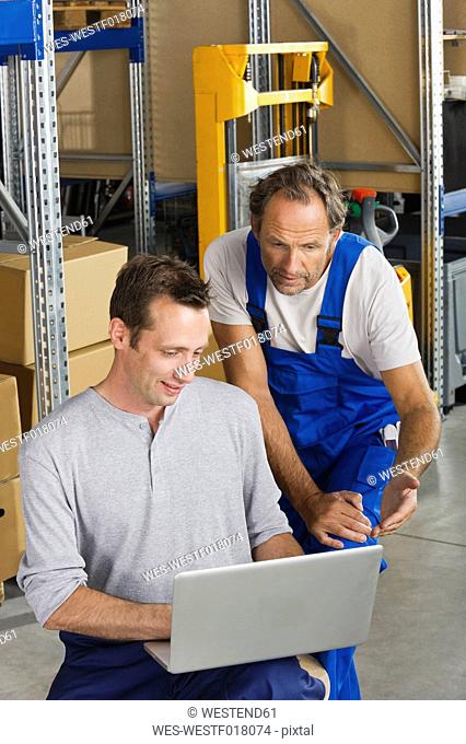 Germany, Bavaria, Munich, Manual workers using laptop in warehouse