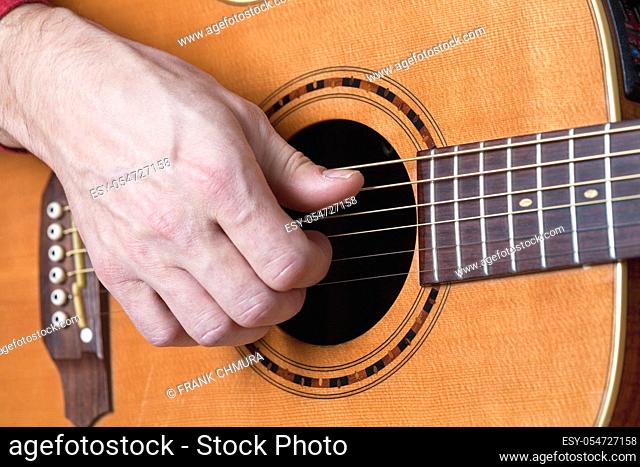 Fingers of a guitar player playing acoustic guitar