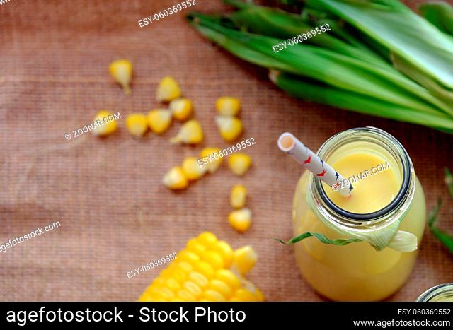 Healthy beverage for breakfast from sweetcorn, corn milk jar in yellow, rich vitamin, tasty, nutrition from maize, fresh milk bottle on wooden background