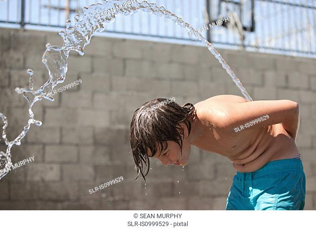 Boy squirting water over his back