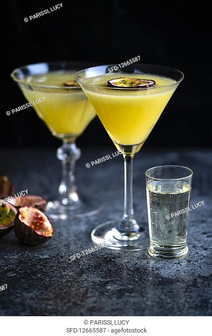 Passion fruit Martini also known as Pornstar Martini in two cocktail glasses decorated with slice of passion fruit with a chaser of Champagne
