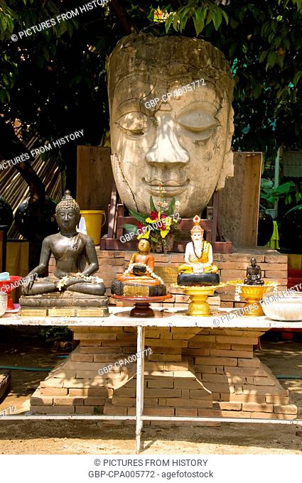 Thailand: Old Buddha head and altar set up for the songkran festival in the grounds of Wat Chetlin, Chiang Mai