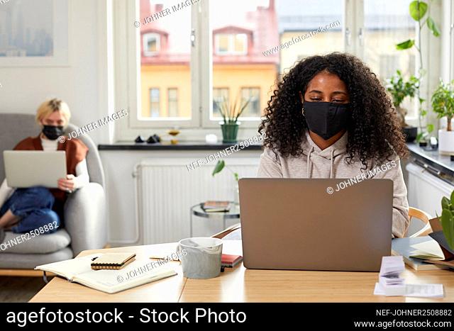 Woman with face mask working in office
