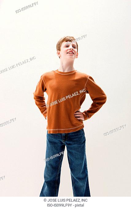 Boy in brown sweater in superhero stance, studio shot