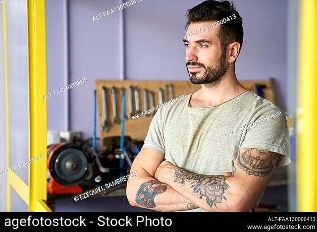 Mid-shot of confident looking bearded bicycle repair shop owner entrepreneur