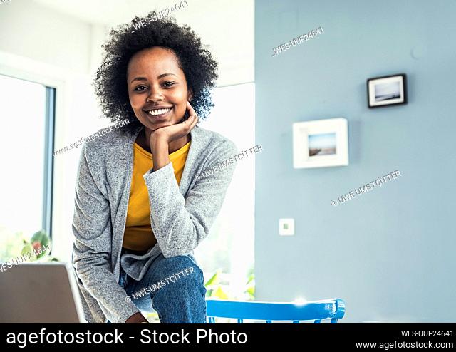 Smiling businesswoman leaning on chair at home office