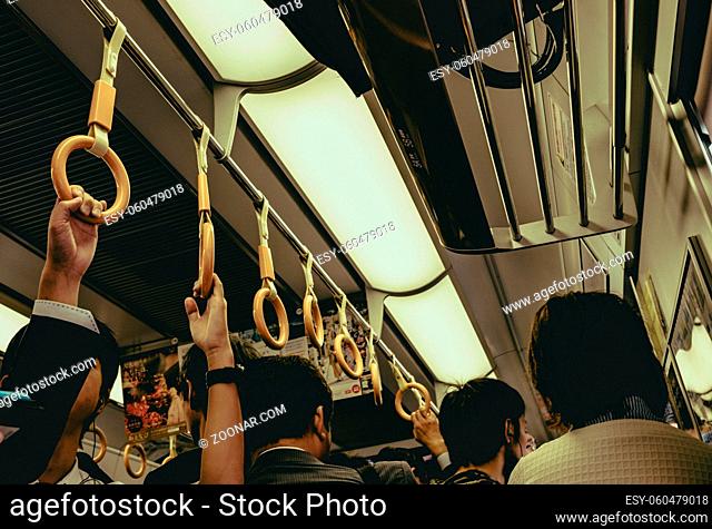 Passenger hand hold strap while standing in subway or sky train in japan