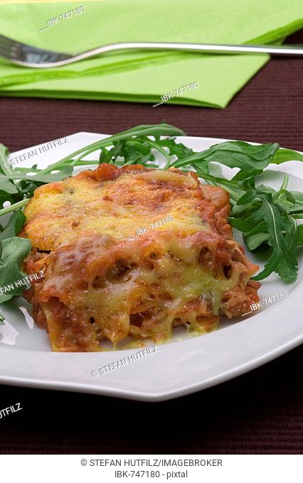Meat lasagna topped with melted cheese beside napkin and fork