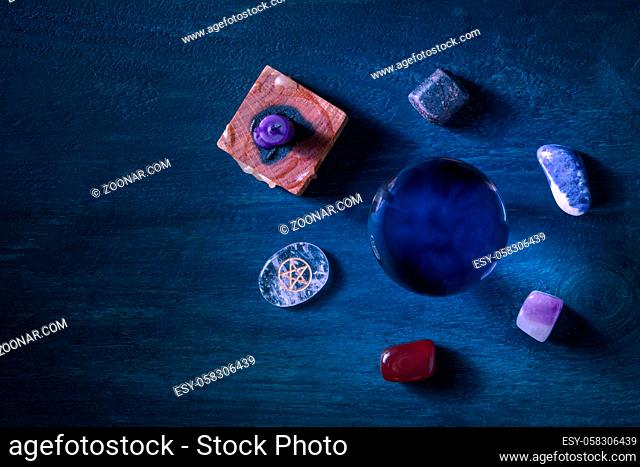 Reading of the future. A magic ball, shot from above with crystals and a candle on a dark background with copy space