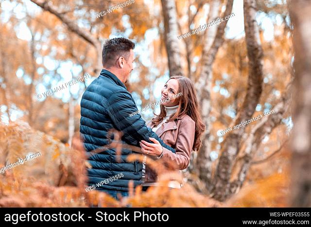 Romantic couple embracing while standing in park during autumn