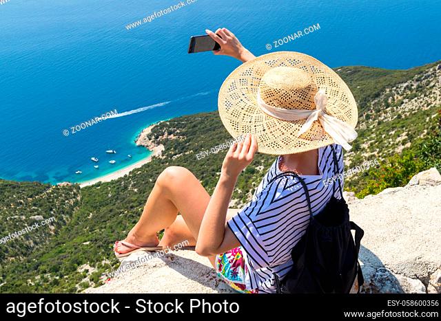 Active sporty woman on summer vacations taking selfie picture while enjoying beautiful coastal view of Cres island, Croatia from Lubenice traditional costal...