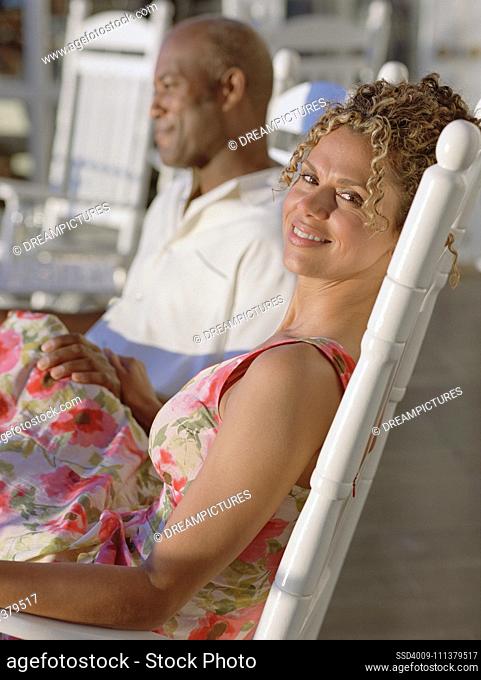 Middle-aged African American couple sitting in rocking chairs outdoors