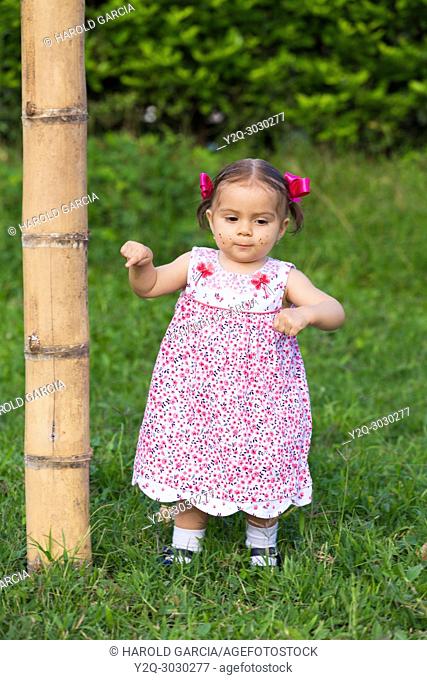 Baby Girl playing in the grass nextto a bambu