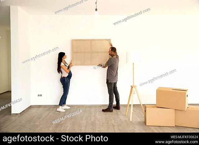 Couple carrying window frame while moving in new house