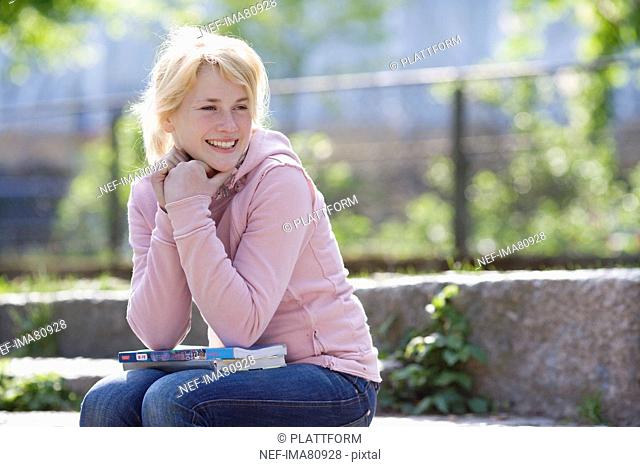 Portrait of smiling teenage girl sitting on stone steps