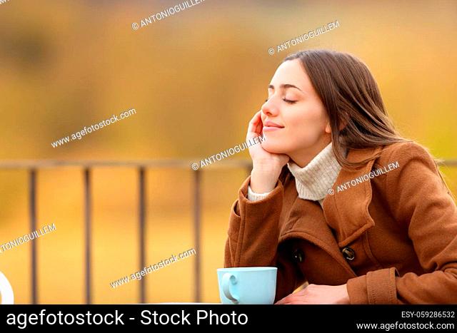 Relaxed woman resting with closed eyes sitting in a coffee shop in winter